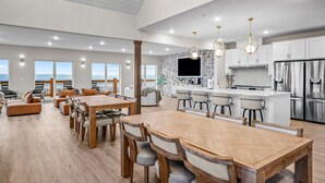 Una cocina amplia con electrodomésticos modernos, un comedor con mobiliario de madera y grandes ventanales con vistas.