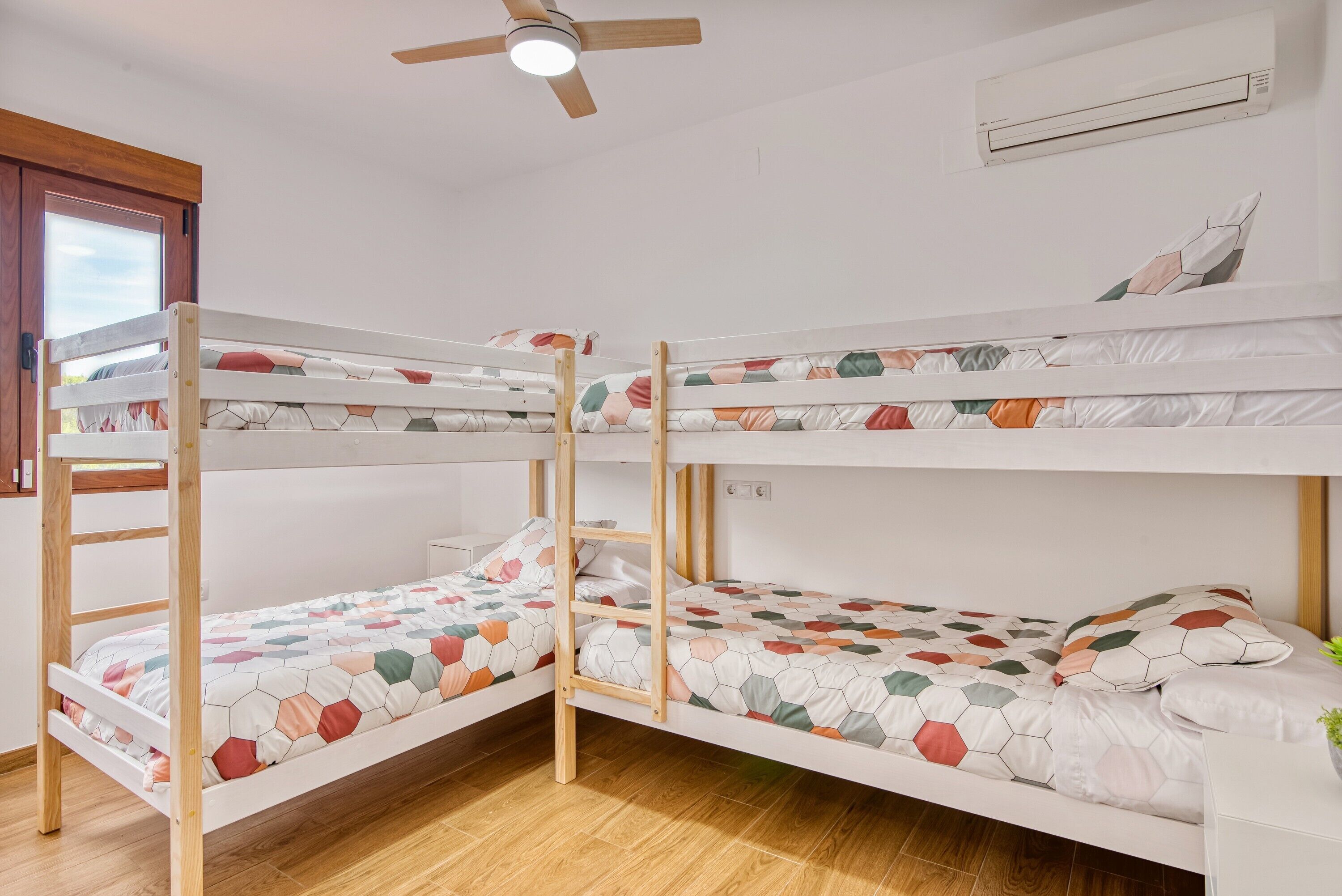 Habitación con literas, ventilador de techo, aire acondicionado y ventana.