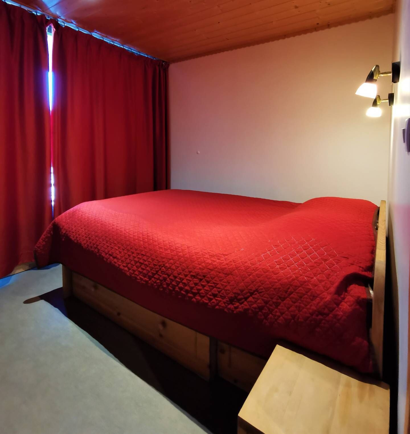 A room with a single bed, wooden headboard, and a small bedside table.
