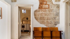 A room with a stone wall, a wooden door, and a tiled floor. - Apartment 'Antica Corte Dell'800' with Private Terrace, Wi-Fi and Air Conditioning (castrignano del capo)