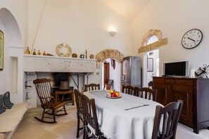 Un espace repas comprenant une table, des chaises, une cheminée et une horloge murale.