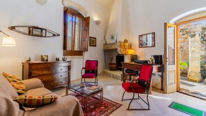 A cozy living room with a fireplace, a wooden desk, and a red chair. - Apartment 'Antica Corte Dell'800' with Private Terrace, Wi-Fi and Air Conditioning (castrignano del capo)