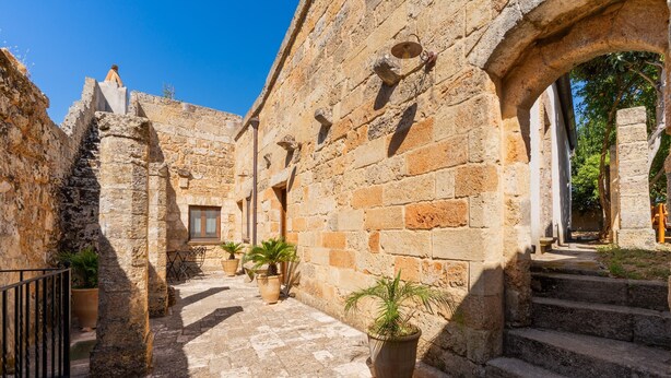 An ancient stone building with a narrow courtyard, potted plants, and a staircase leading to an upper level. - Apartment 'Antica Corte Dell'800' with Private Terrace, Wi-Fi and Air Conditioning (castrignano del capo)