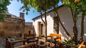 An outdoor seating area with wooden furniture and a stone wall in the background. - Apartment 'Antica Corte Dell'800' with Private Terrace, Wi-Fi and Air Conditioning (castrignano del capo)