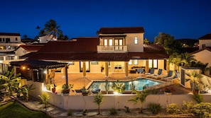A two-story house with a swimming pool, outdoor seating, and a covered patio area.