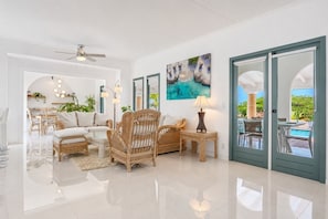 A spacious living area with a sofa, chairs, a coffee table, a lamp, and a painting on the wall.