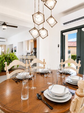 A dining area with a round wooden table set for six, surrounded by wooden chairs.