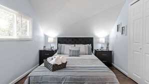 Ein Schlafzimmer mit einem großen Bett, zwei Nachttischen, einem Fenster mit Jalousien und einem Kleiderschrank.