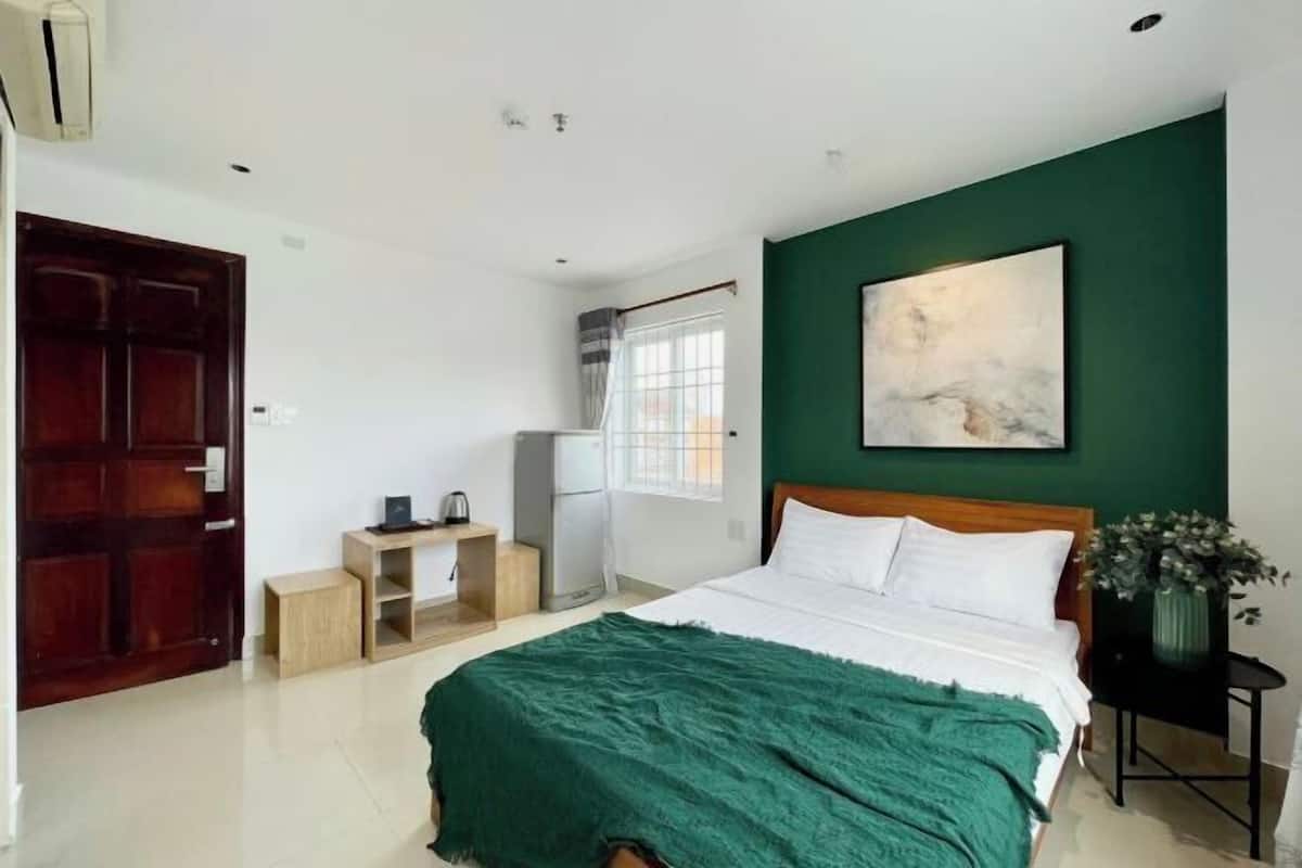 Une chambre à coucher avec un lit, un bureau, une chaise, une fenêtre et une porte.