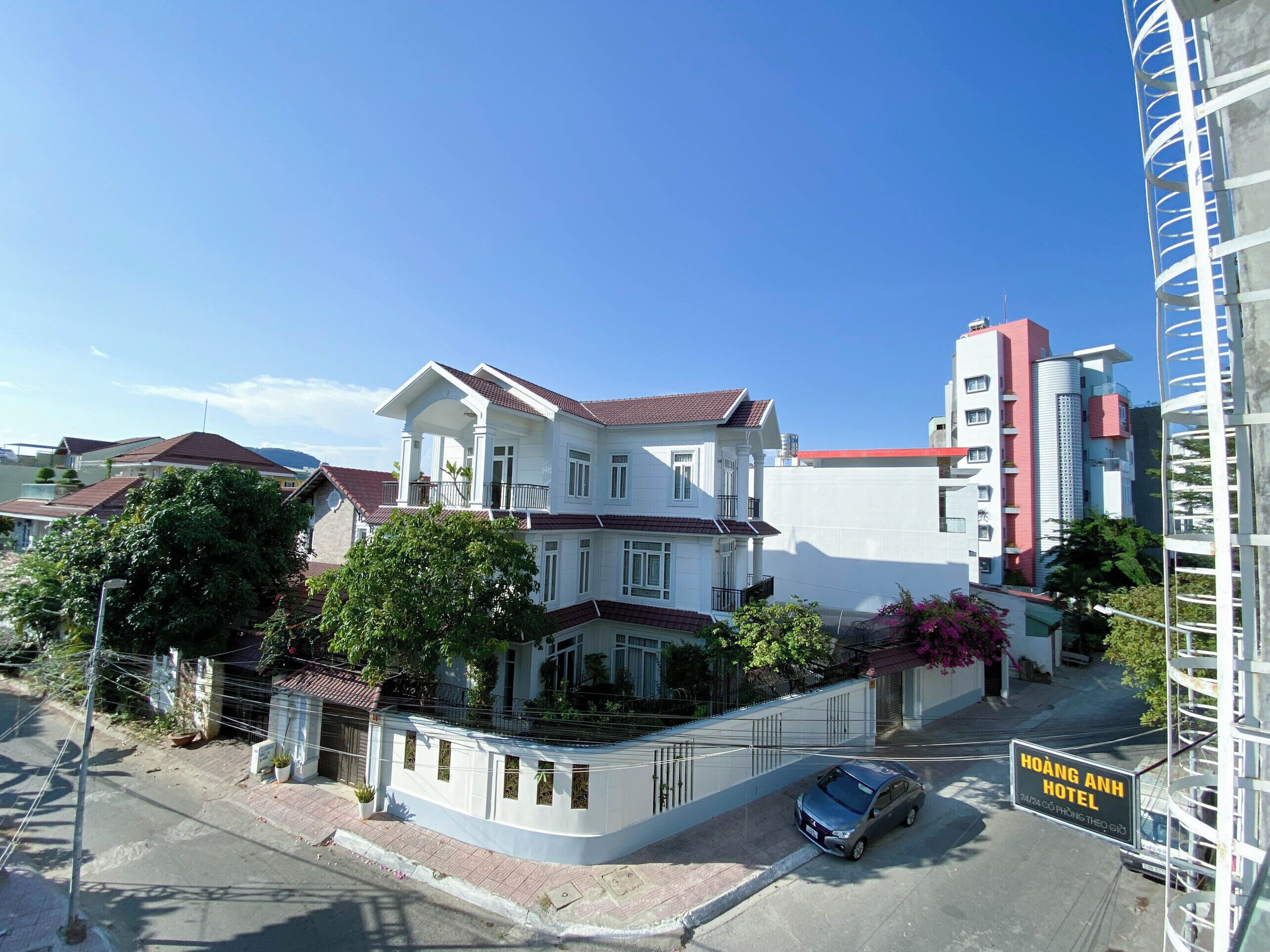 A two-story building with a balcony, a car parked in front, and a sign for Hoàng Anh Hotel.