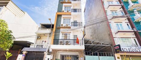 A multi-story hotel with a modern facade, a gated entrance, and several parked motorcycles.