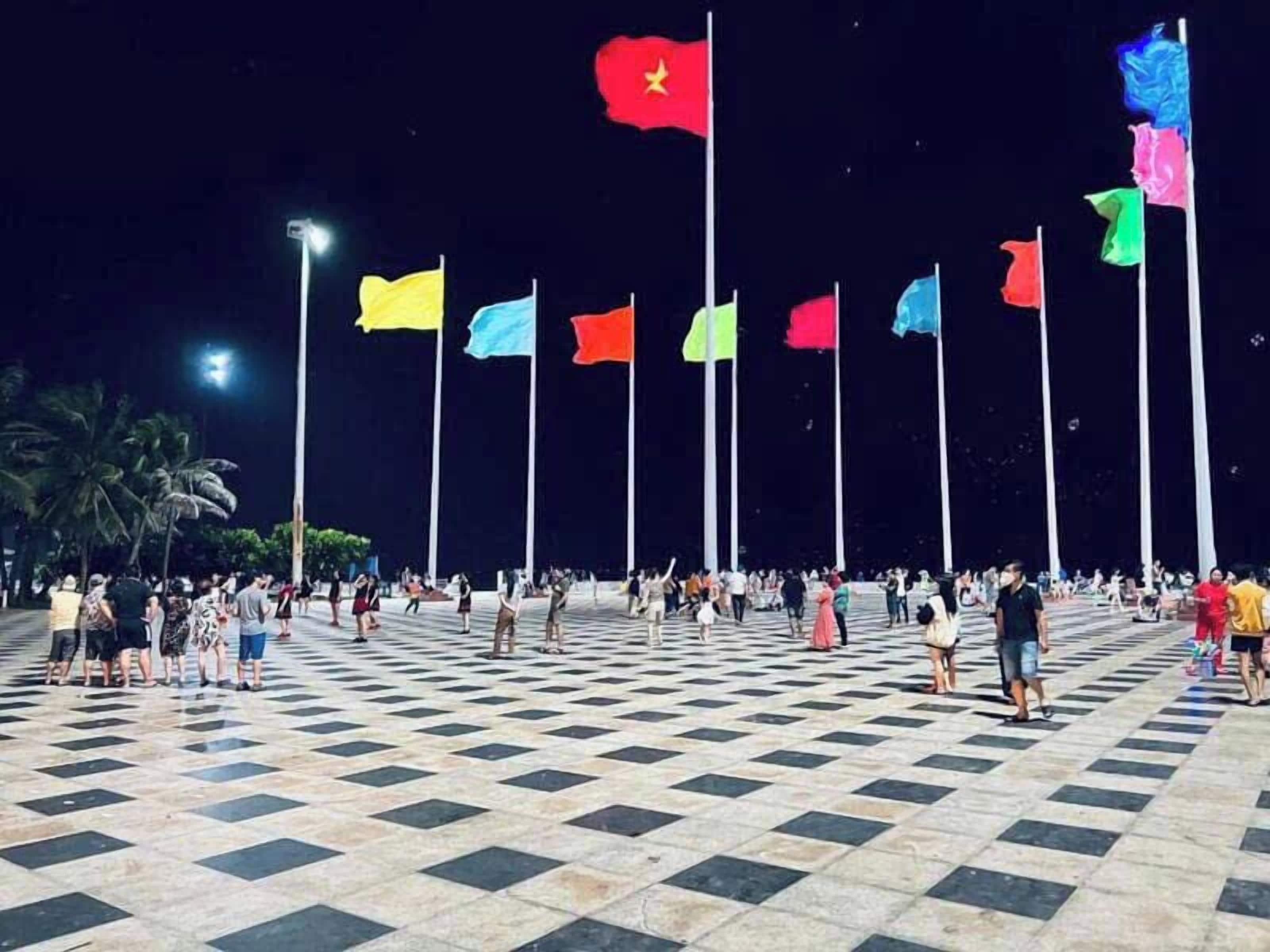 A plaza with a checkered floor and multiple flagpoles with flags.