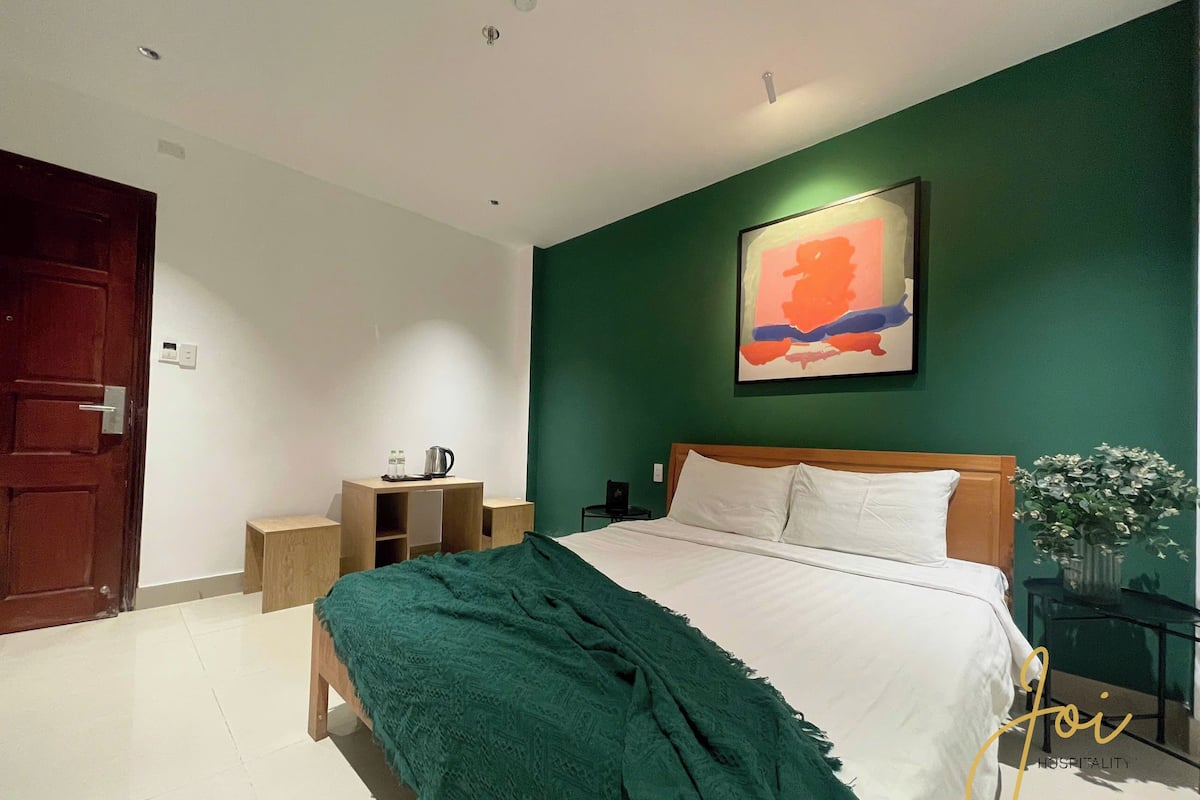 Une chambre d’hôtel avec un lit, une table de chevet, un tableau et une porte.