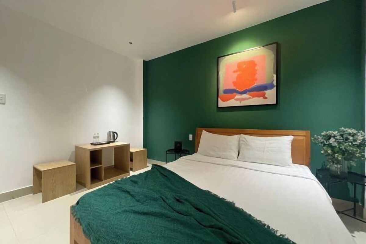 Une chambre à coucher avec un lit, une table de chevet, une armoire en bois et un mur vert.