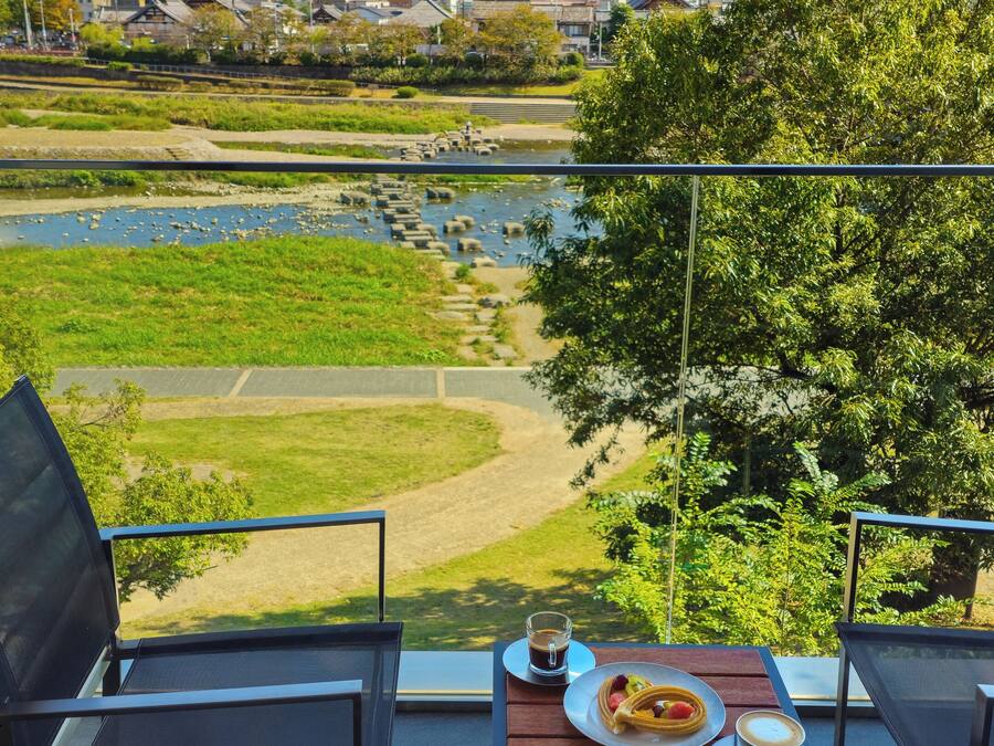 Un balcon avec une table dressée pour deux personnes, donnant sur une rivière et une ville.