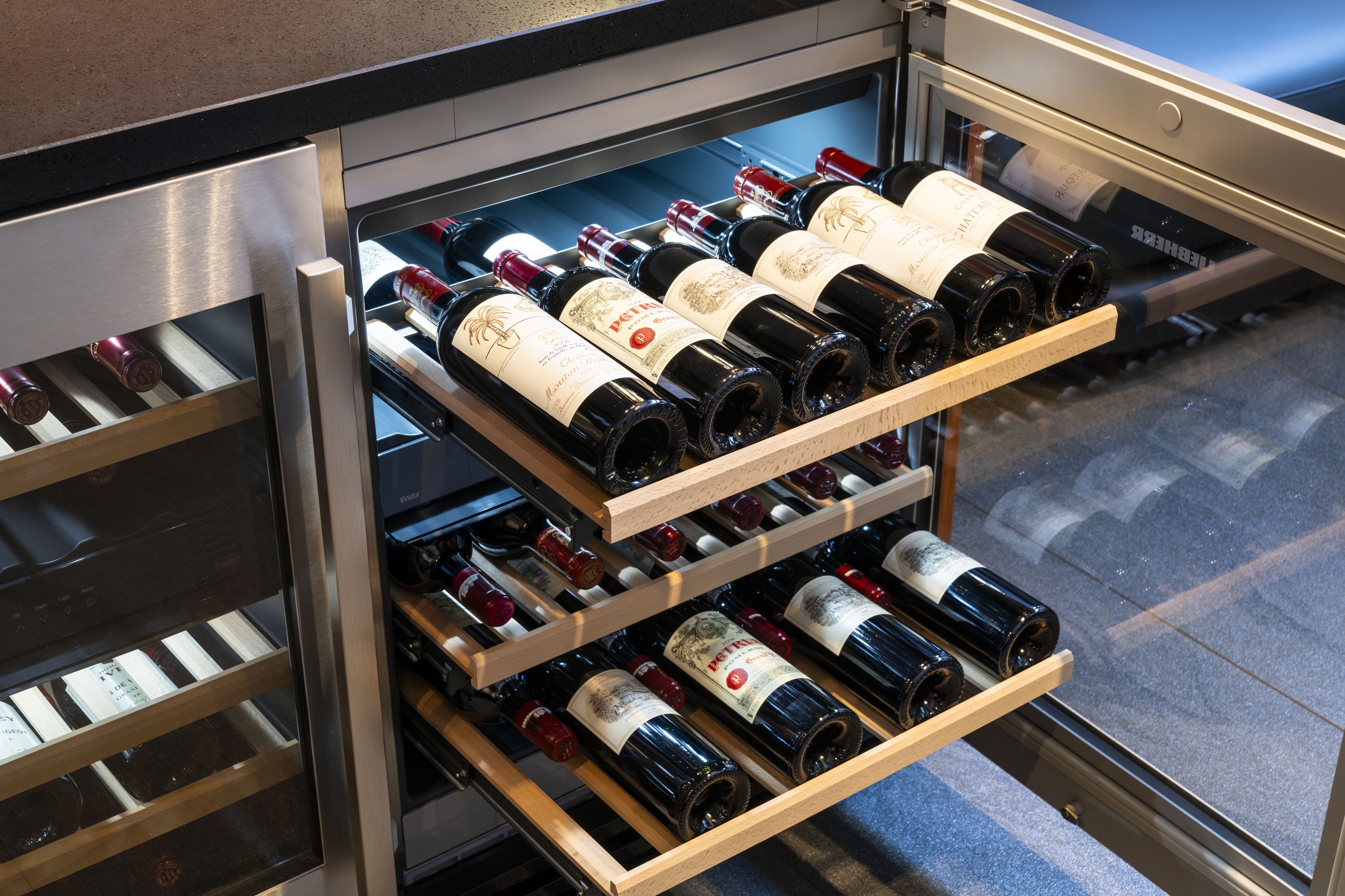 A wine rack with multiple bottles inside a glass-fronted cabinet.