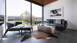 A modern living room with a large window, a black leather sofa, a glass coffee table, and a framed photograph on the wall. - Kamo Residences by Reflections (Kyoto)