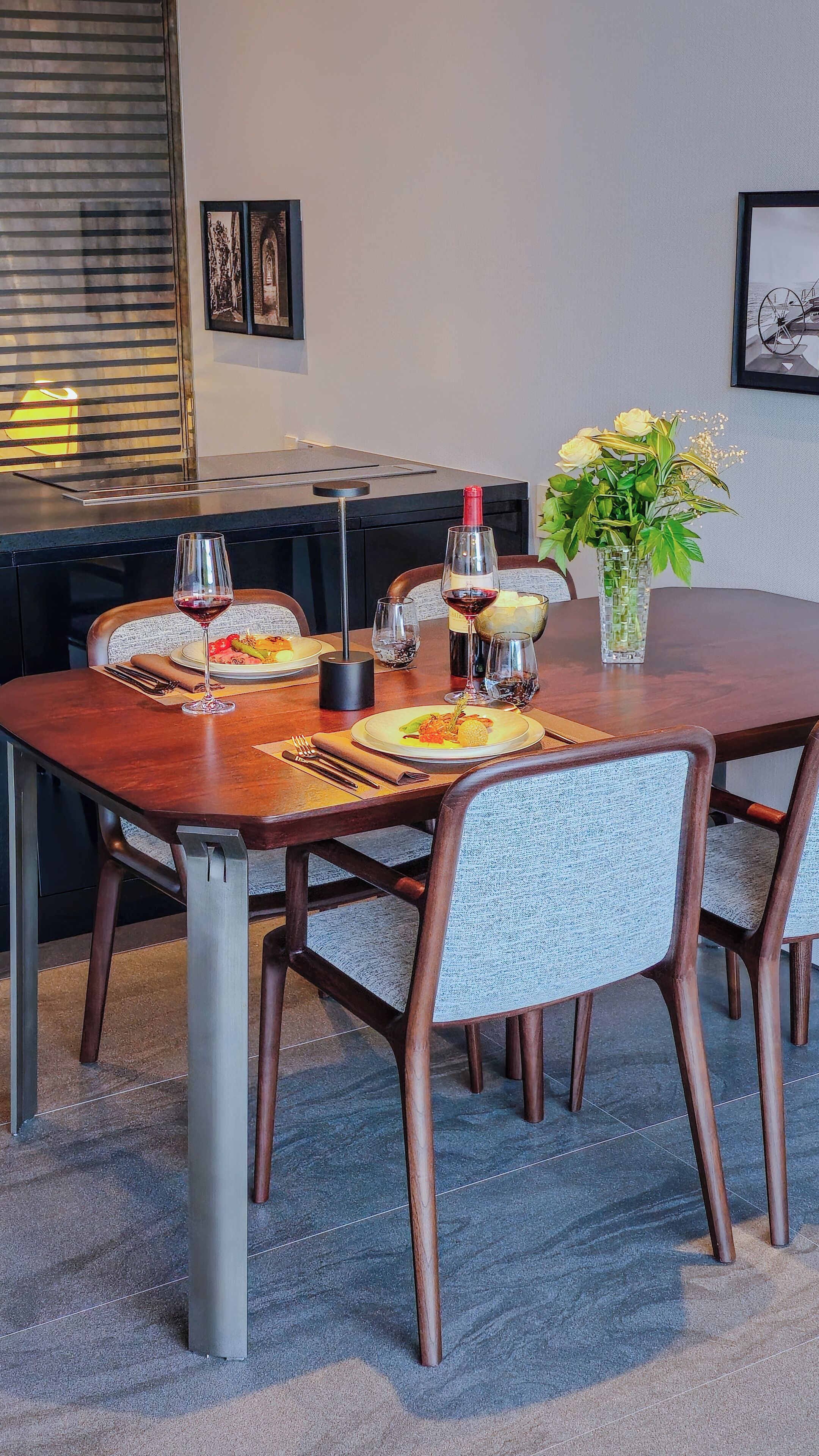 A dining table set with plates, glasses, and a vase of flowers.