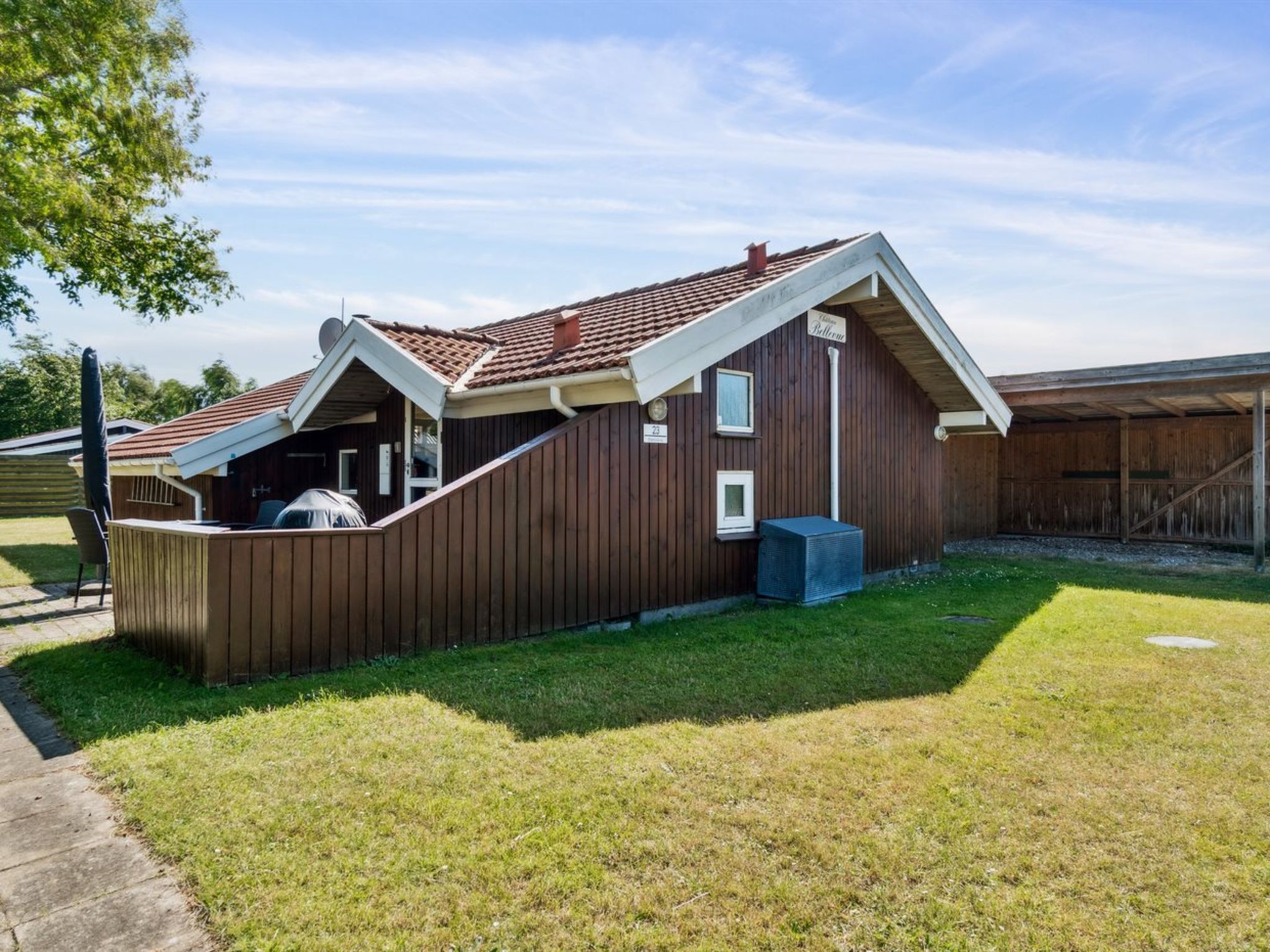 Ein Holzhaus mit geneigtem Dach und einer kleinen angeschlossenen Garage.