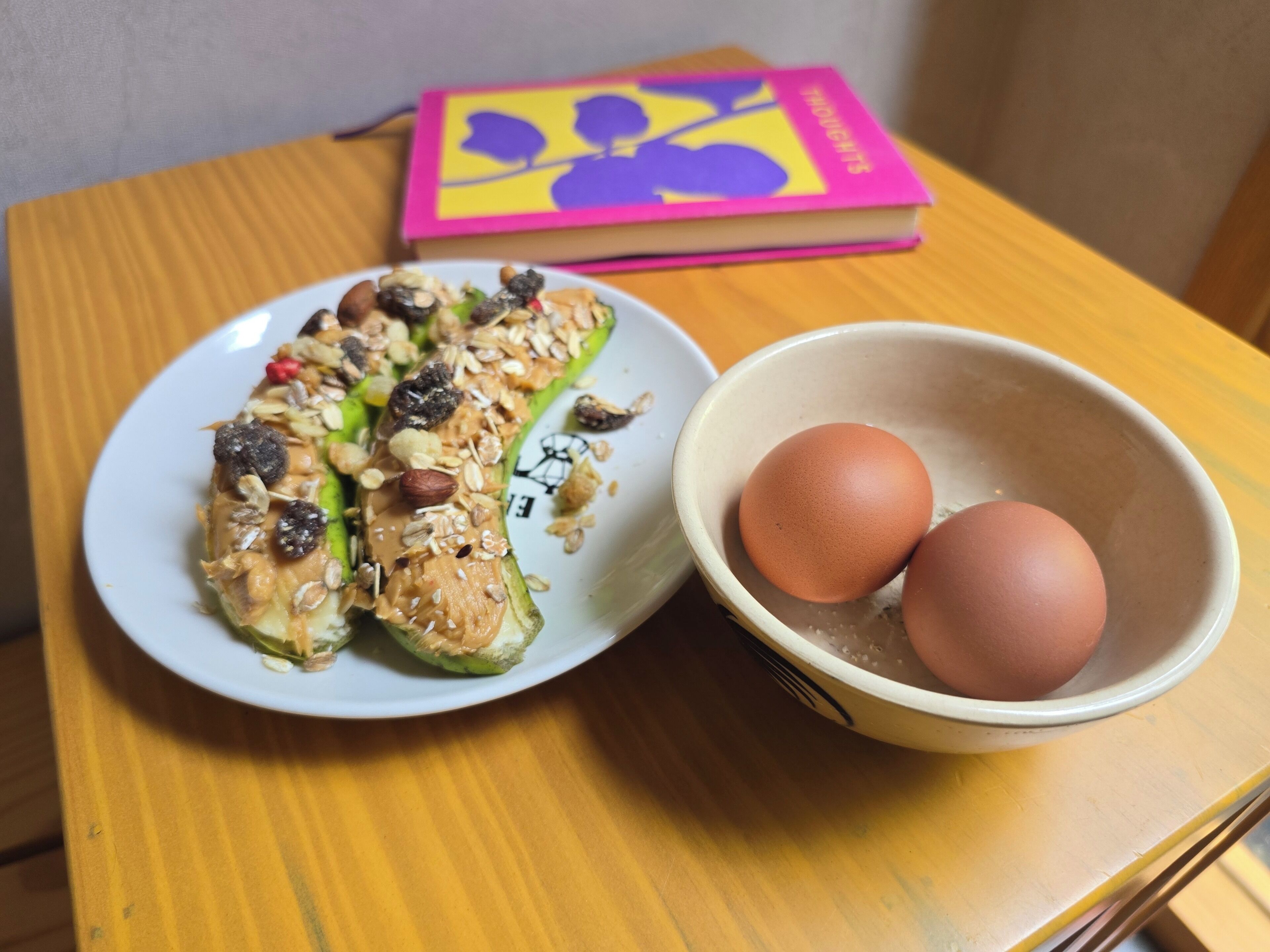 A plate of stuffed vegetables with nuts and seeds, and a bowl with two eggs on a wooden table.