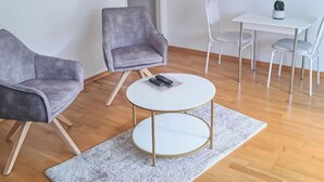 A modern living room with two grey armchairs, a white coffee table, and a dining table with white chairs. - Kitzblick by Interhome (Zell am See)