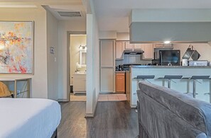 A modern hotel room with a large bed, a kitchenette, a dining area with bar stools, and a bathroom with a shower and toilet. - Your Montrose Estate! Sleeps 18/8BR/4BA/4PA<br> (Houston)