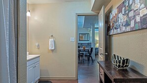 A hallway with a wooden floor, a white door, a small table with chairs, and a wall-mounted light fixture. - Your Montrose Estate! Sleeps 18/8BR/4BA/4PA<br> (Houston)