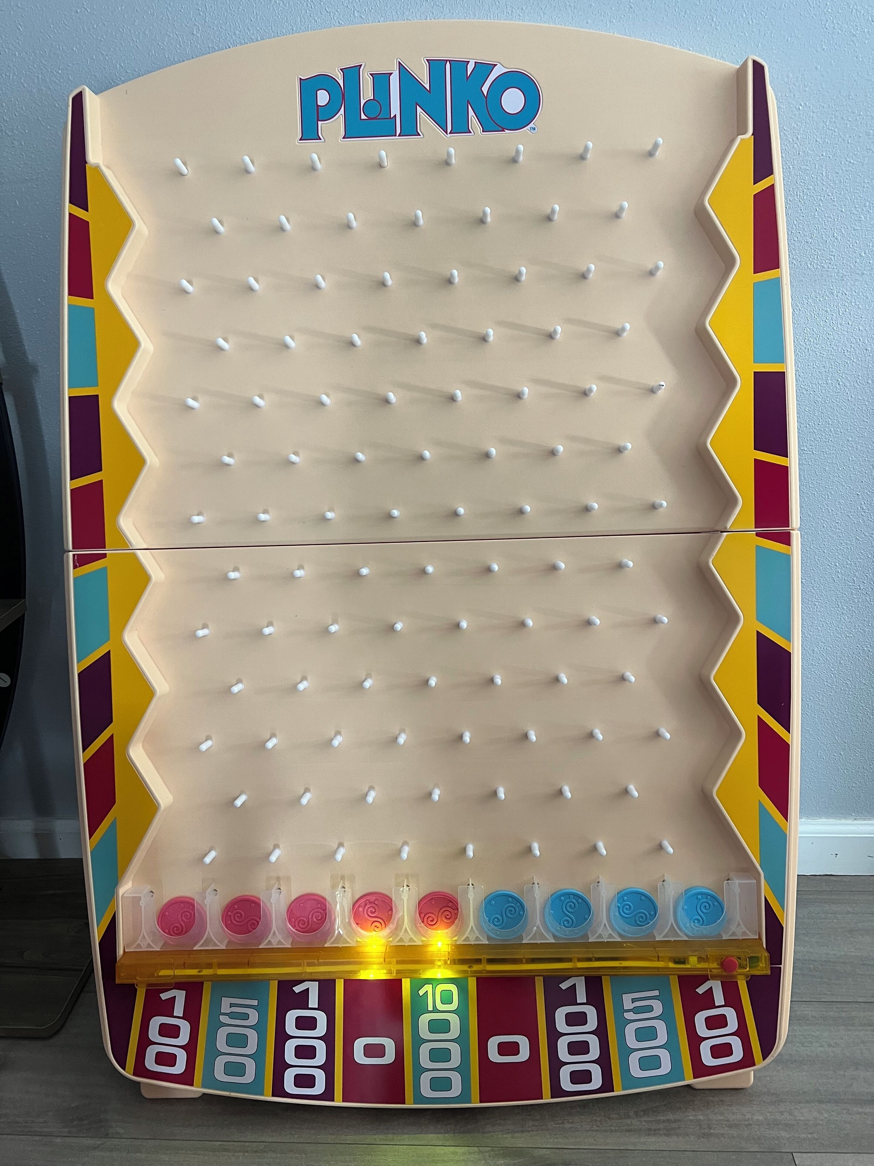 A Plinko board game with a colorful border and numbered scoring areas.