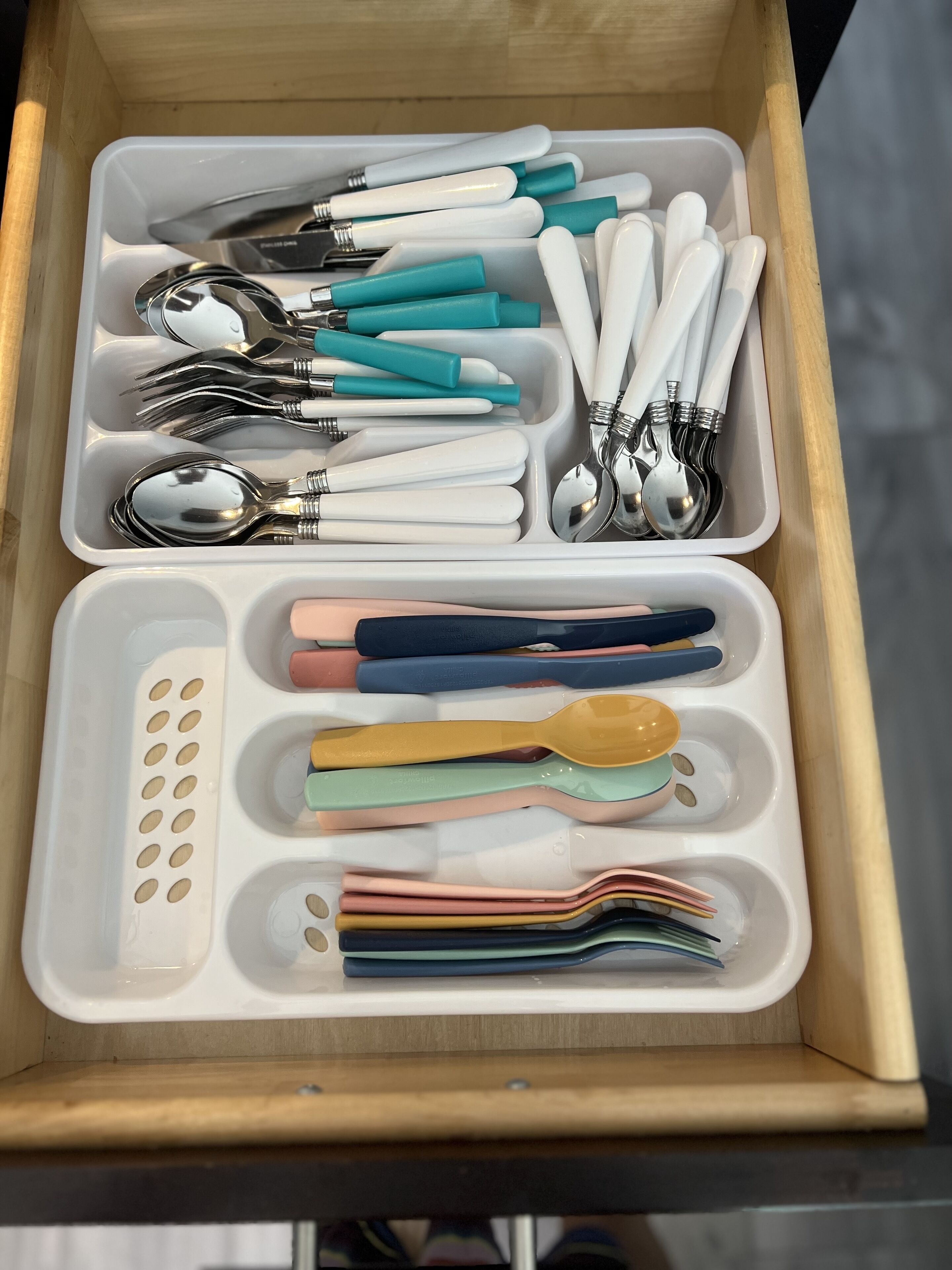 A drawer containing various utensils and kitchenware, including spoons, forks, and knives, organized in compartments.