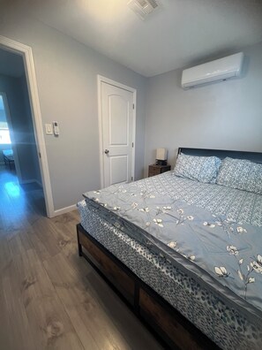 Een slaapkamer met een bed, een deur, een airconditioning en een nachtkastje.