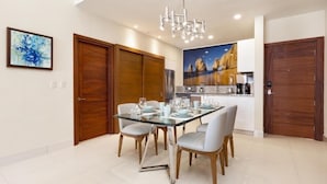 A dining area with a glass table, four chairs, and a modern chandelier. -  VILLA LA VALENCIA, LOS CABOS, TWO BEDROOM OCT28-NOV5TH (San José del Cabo)