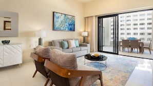 A modern living room with a sofa, armchairs, a coffee table, and a dining area with a view of a building through large windows. -  VILLA LA VALENCIA, LOS CABOS, TWO BEDROOM OCT28-NOV5TH (San José del Cabo)
