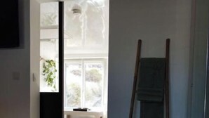 A room with a wooden floor, a ladder leaning against the wall, and a window with a view of the outdoors. - Appartement Proche Gare et Centre-ville D'amiens (Rivery)