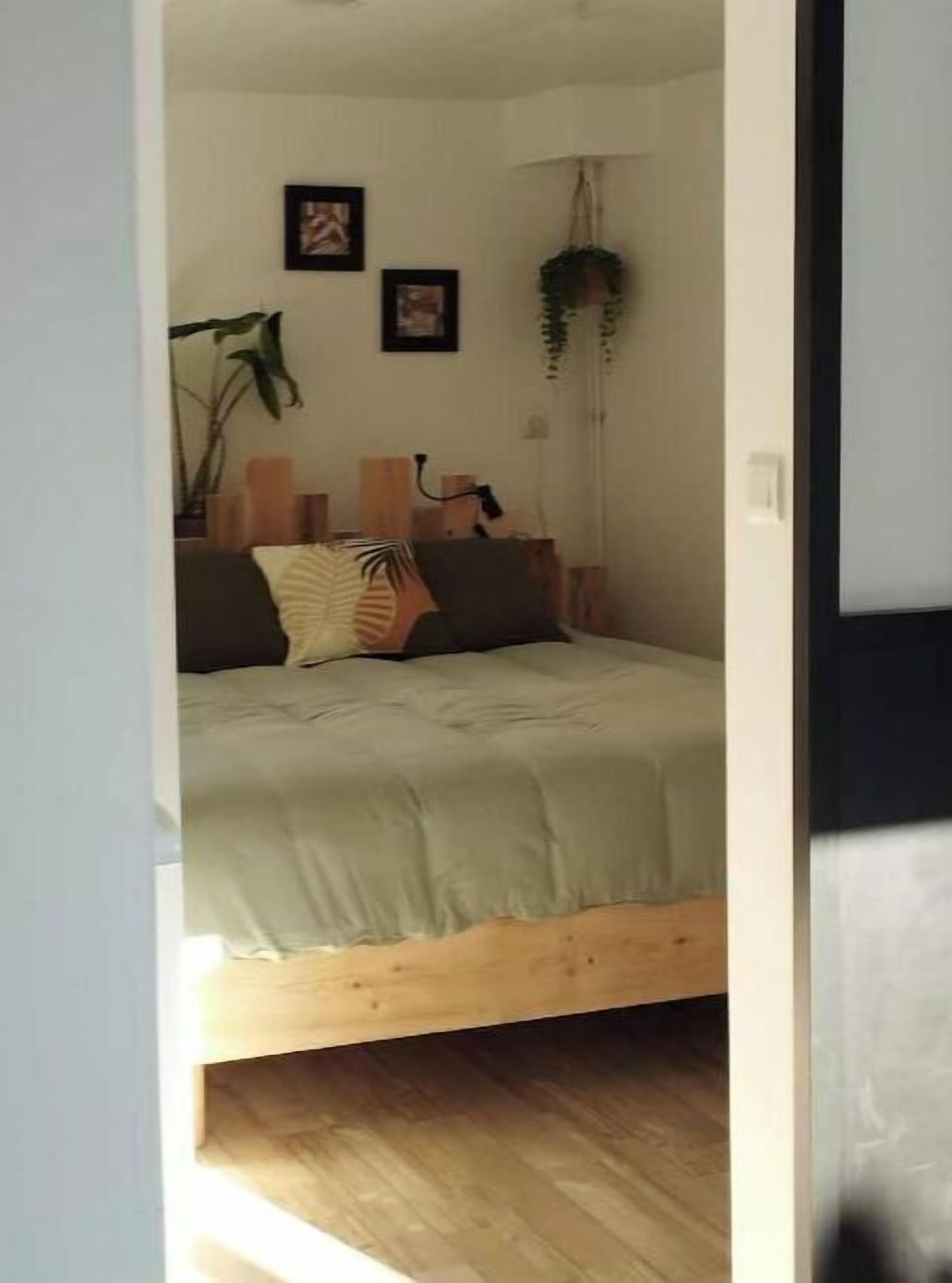 Ein Schlafzimmer mit einem Bett, einer hängenden Pflanze und gerahmten Bildern an der Wand.
