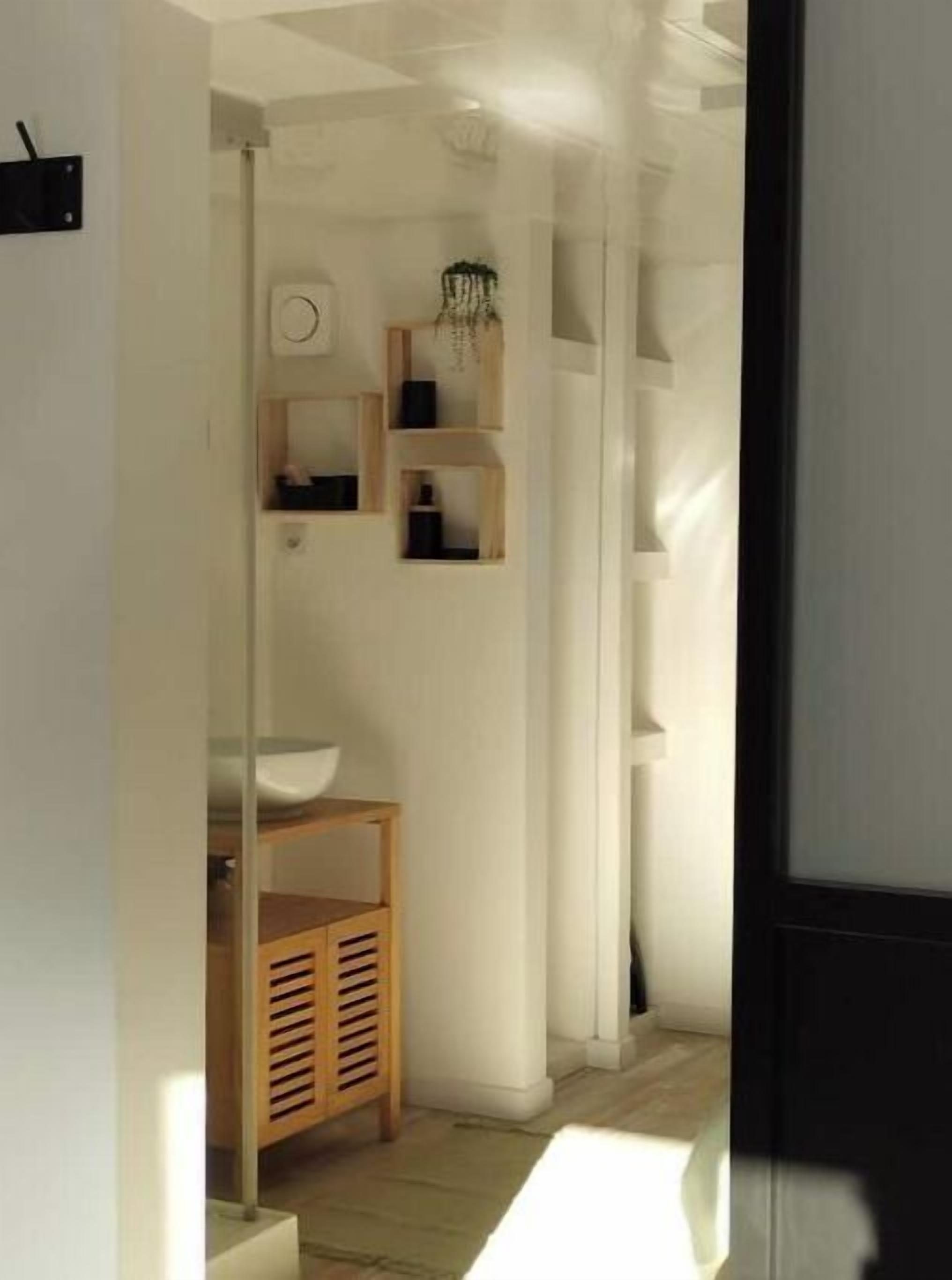 A modern bathroom with a wooden vanity, a sink, and built-in shelves.