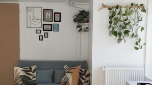 A modern living room with a blue sofa, decorative pillows, a wooden coffee table, and a white radiator. - Appartement Proche Gare et Centre-ville D'amiens (Rivery)