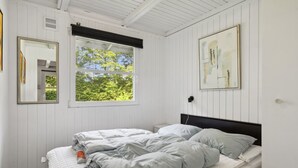 A bedroom with a bed, a window, a painting, and a mirror.