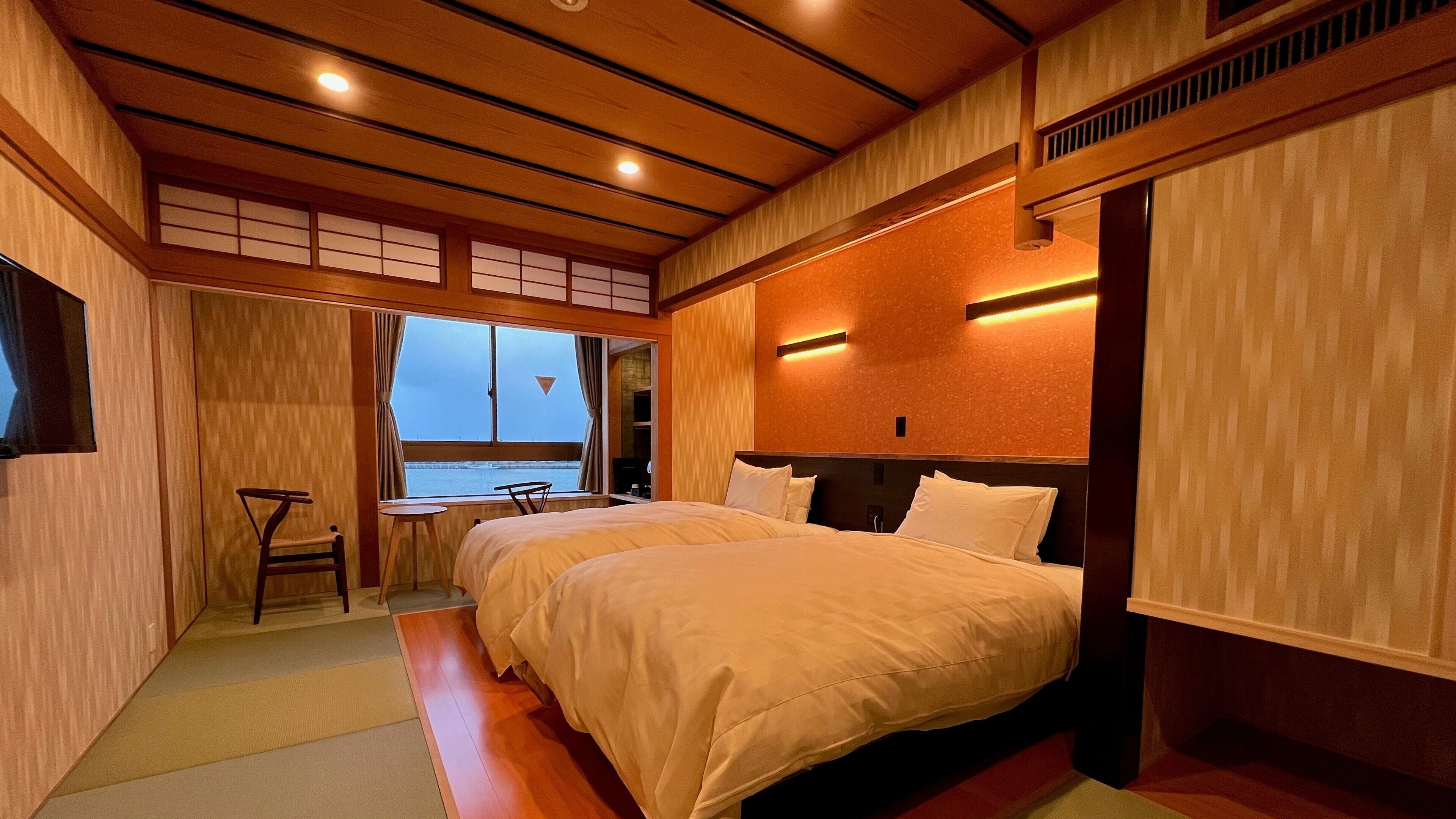 Ein Hotelzimmer mit einem großen Bett, einem kleinen Tisch und Meerblick durch ein Fenster.