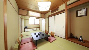 A traditional Japanese room with tatami flooring, a low table with tea sets, sliding doors, and a small shelf with decorative items. - Mikakunooyado Yamadaya (Tottori)
