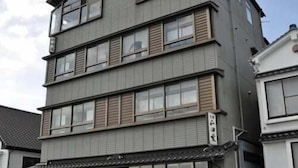 A multi-story building with a flat roof, large windows, and a visible entrance with steps leading up to it. - Mikakunooyado Yamadaya (Tottori)