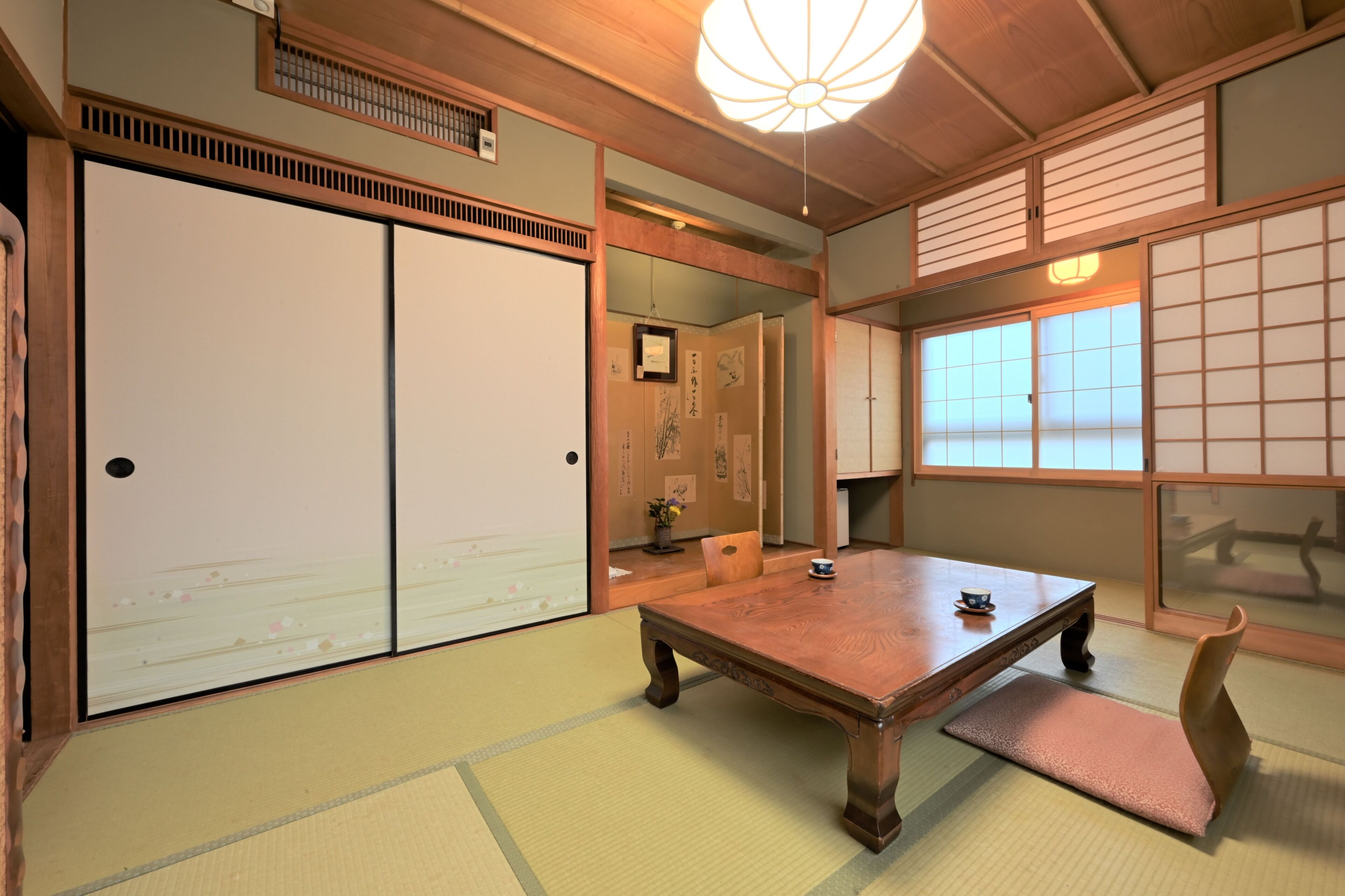 Ein traditioneller japanischer Raum mit Tatami-Böden, einem Holztisch, Schiebetüren und einem Shoji-Bildschirm.
