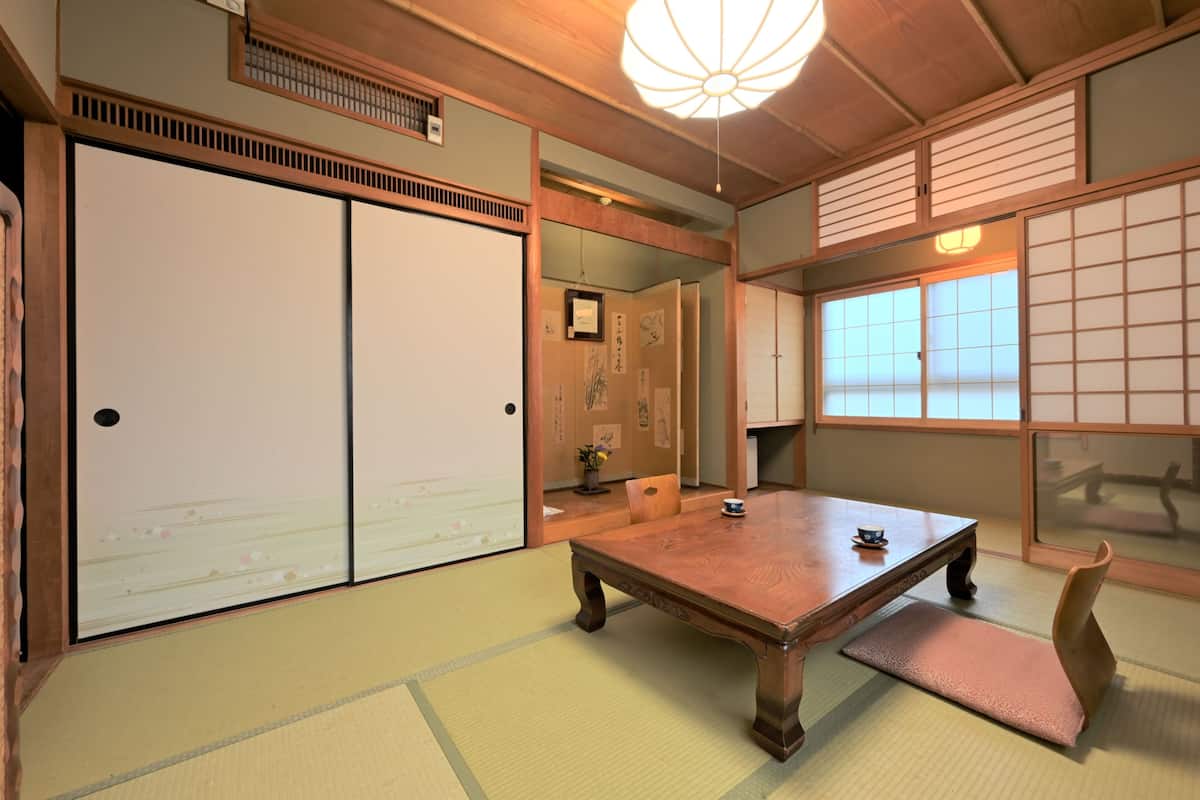 Une pièce de style japonais traditionnel, avec un sol recouvert de tatamis, une table en bois, des portes coulissantes et un paravent shoji.
