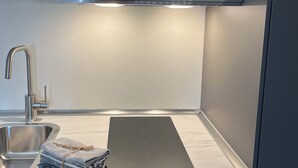 A modern kitchen with a stainless steel sink, a black cutting board, and a neatly folded towel.