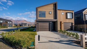 A modern two-story house with a garage, a driveway, and a well-maintained lawn. - Wanaka Wonder - Wanaka Holiday Home (Wanaka)