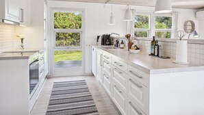 A modern kitchen with white cabinetry, a large window, and a view of greenery outside.