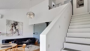 A modern interior with a staircase, a dining area with a round table and chairs, and a large abstract painting on the wall. - "Virpi" - 1km from the sea by Interhome (Blokhus)