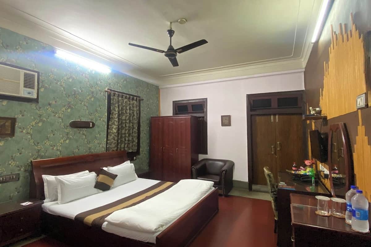 A hotel room with a bed, a desk, a chair, a ceiling fan, and a wardrobe.