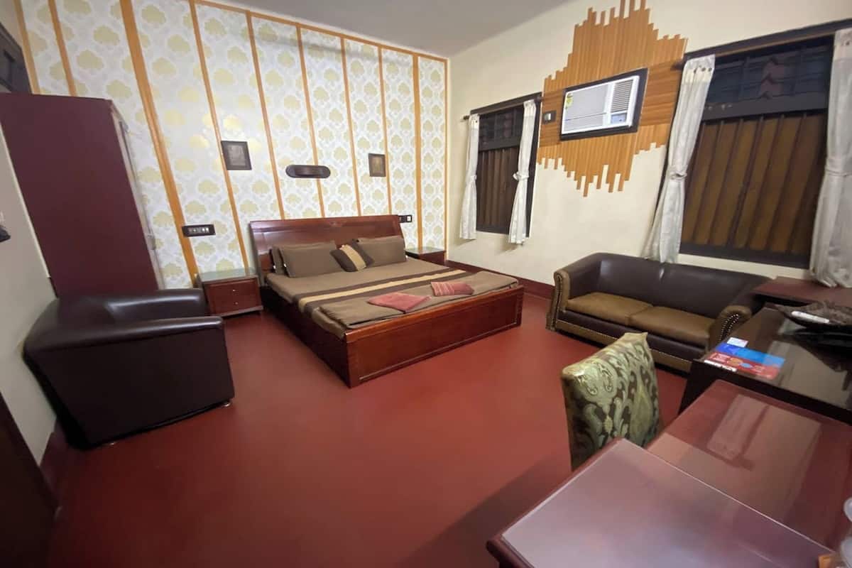 A hotel room with a bed, a sofa, a desk, and a wardrobe.