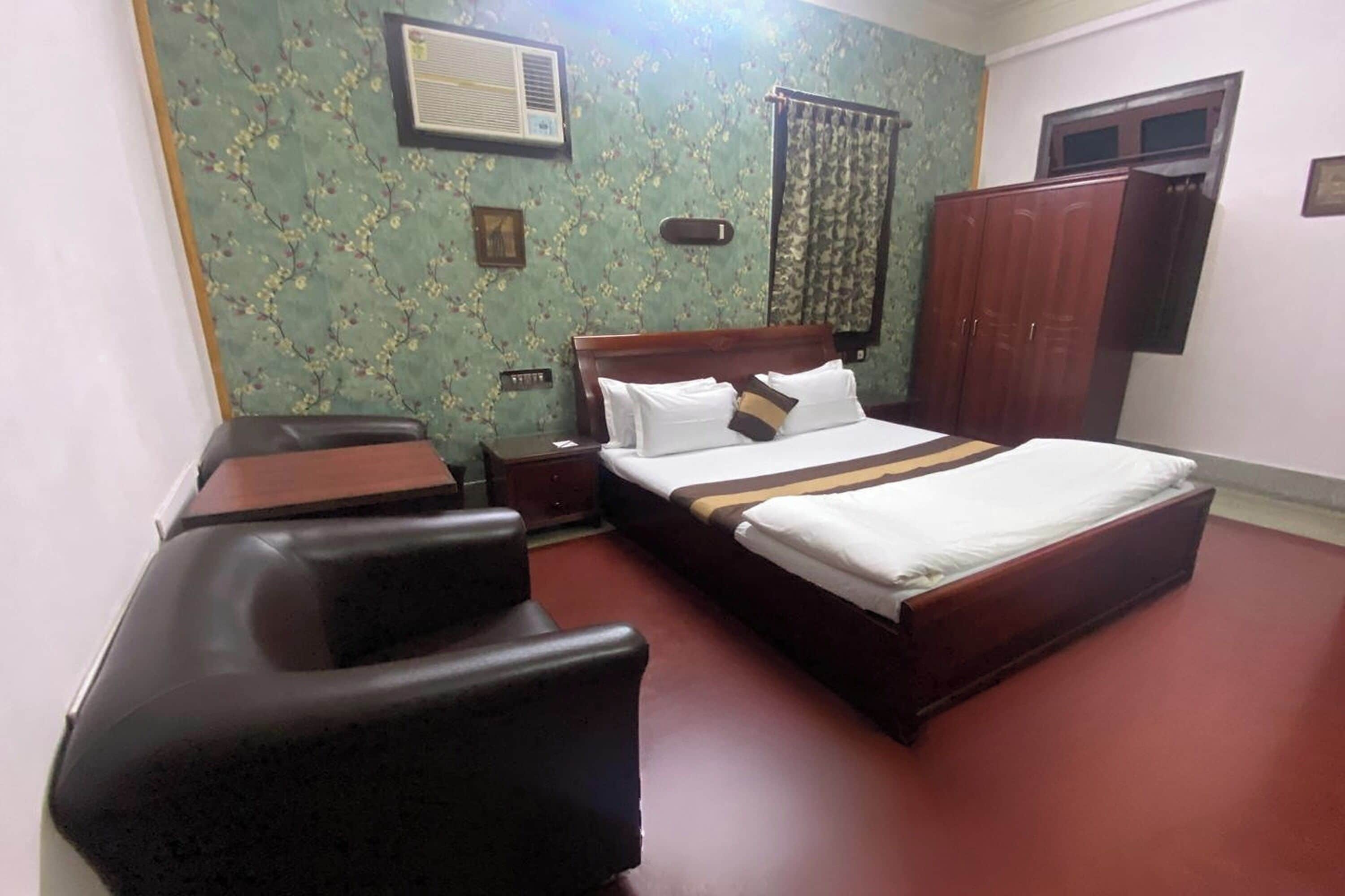 Een slaapkamer met een groot bed, een houten nachtkastje, een bureau en een kledingkast.