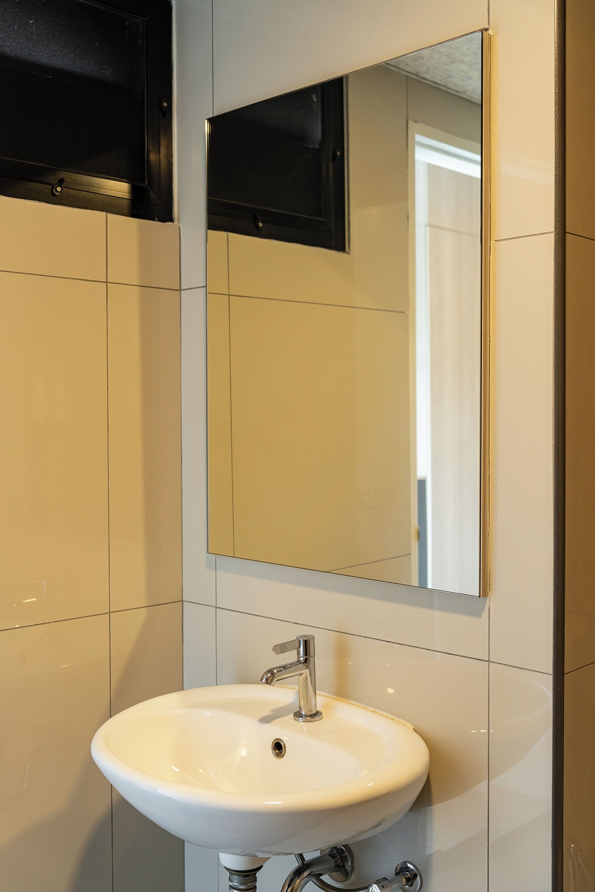 Une salle de bain avec un lavabo blanc, un miroir et des murs carrelés.